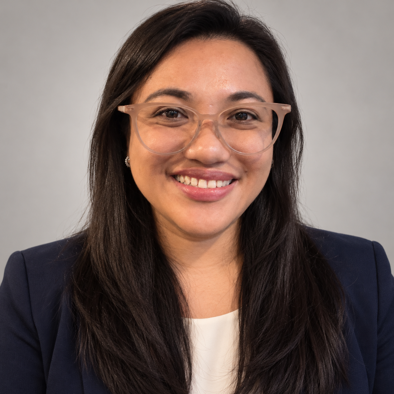 Nikka Nava smiling, wearing glasses and a navy blazer